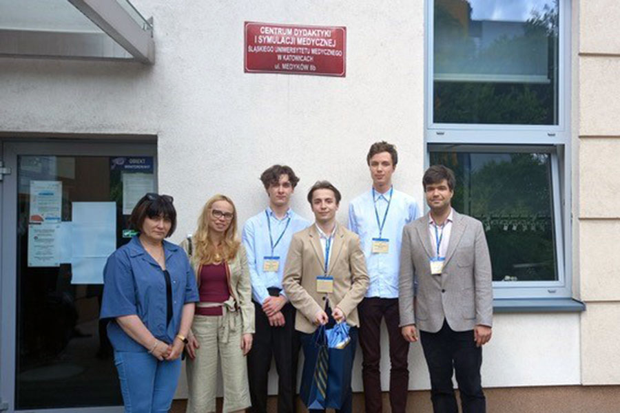 A group of people, on the left two women, on the right four men. They stand in front of the building and pose for a photo.