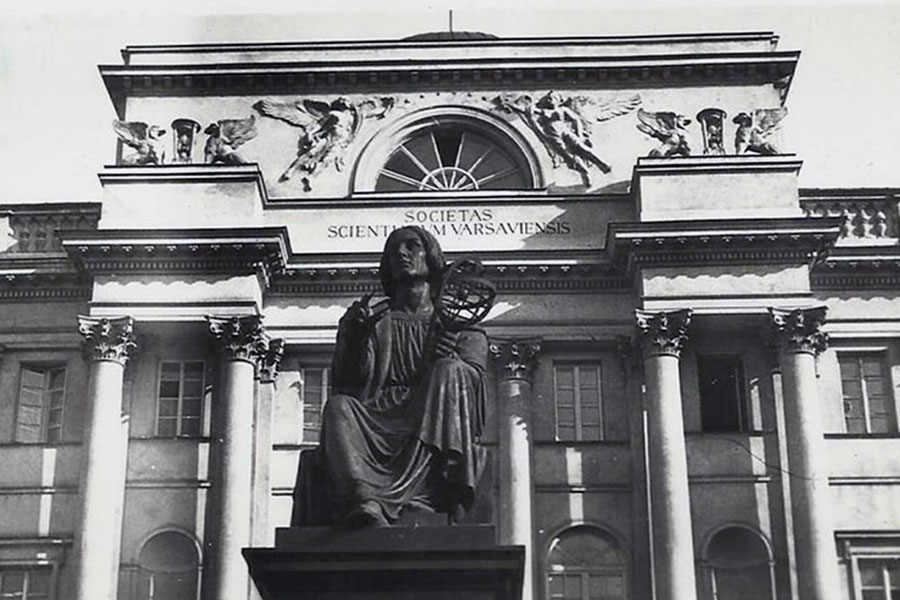 Budynek z kolumnami i ozdobnym gzymsem, przed budynkiem pomnik Kopernika