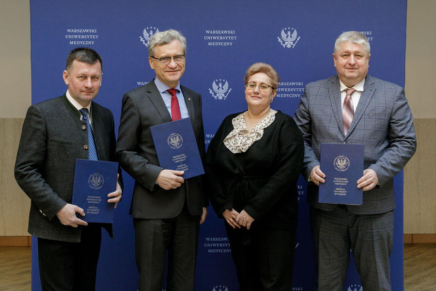 Grupa elegancko ubranych osób, trzech mężczyzn i kobieta pozuje do zdjęcia,