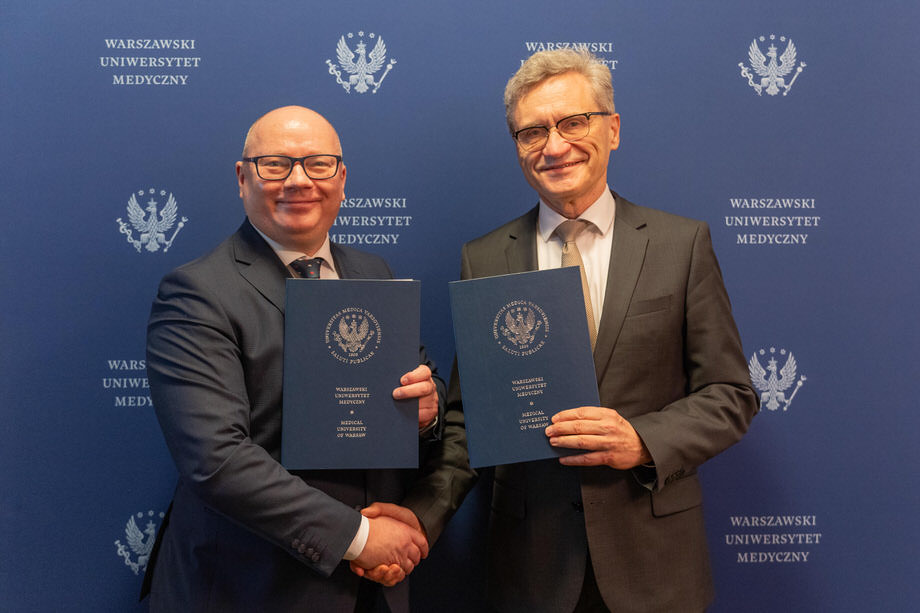 Two elegantly dressed men - the rectors of WUM and PG - shake hands, while the other holds folders with signed agreements. They smile.