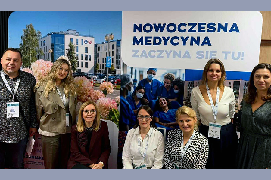 Grupa uczestników z WUM, którzy pozują do zdjęcia na tle baneru "Nowoczesna medycyna".