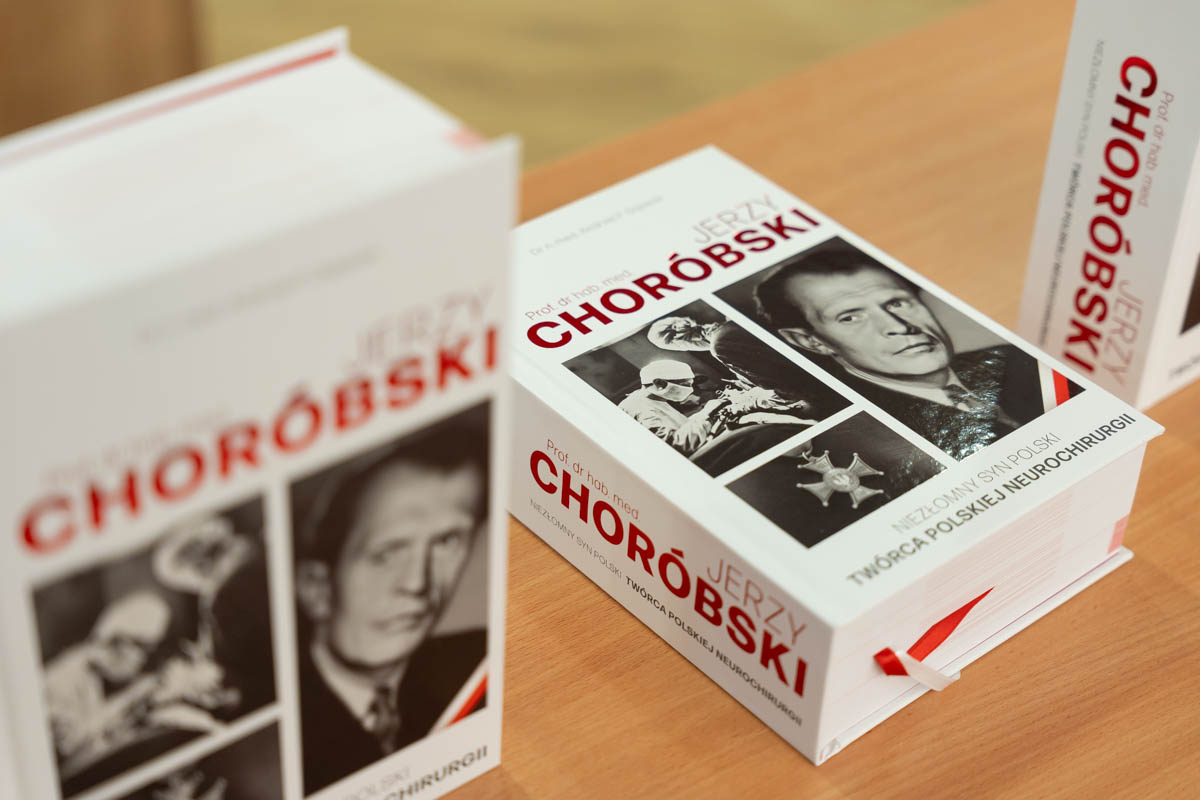 Trzy egzemplarze książki zatytułowanej „Jerzy Choróbski” z białymi okładkami, czerwonymi i czarnymi napisami oraz czarno-białymi zdjęciami Jerzego Choróbskiego.