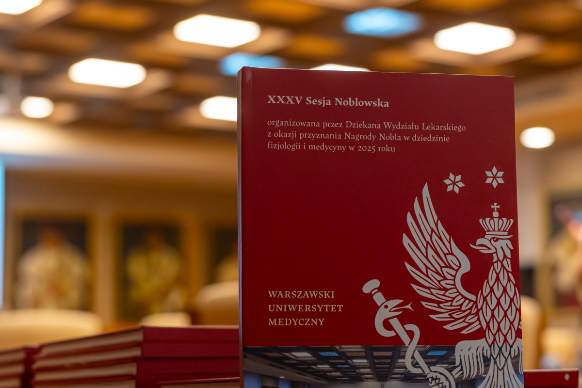 A red cover of a publication featuring a white image of an eagle and a medical symbol, announcing the 35th Nobel Session organized by the Dean of the Faculty of Medicine at the Medical University of Warsaw on the occasion of awarding the Nobel Prize in Physiology or Medicine in 2025; in the background, a blurred bright interior of a conference hall.