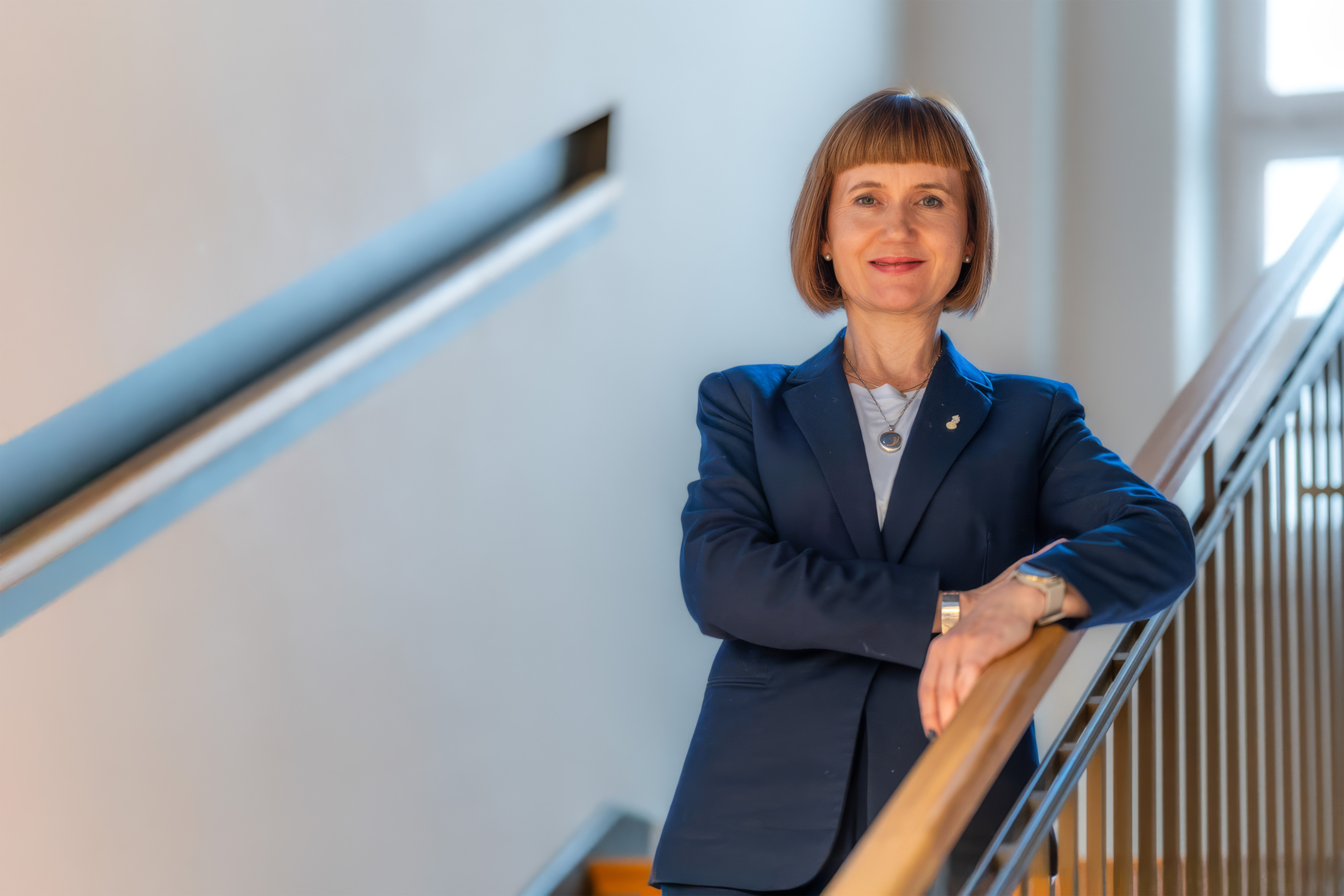 A woman is standing on the stairs, leaning against the railing.