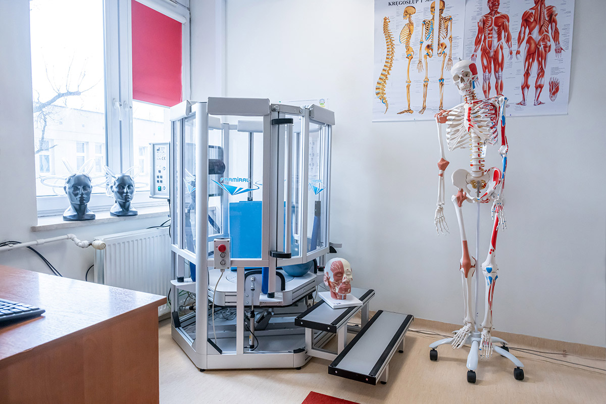 A rehabilitation room equipped with an advanced exercise device, featuring an anatomical skeleton model and posters illustrating the structure of the skeletal and muscular systems.”