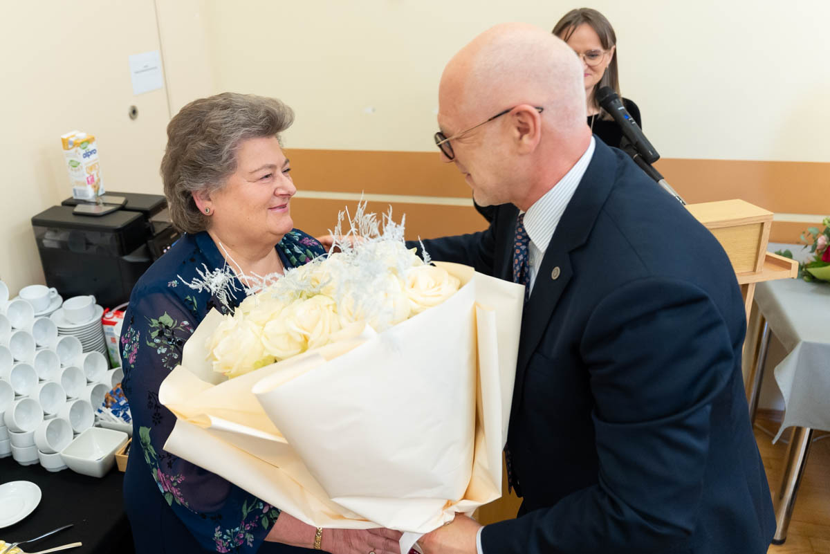 A person is presenting a large bouquet of light-colored flowers during a ceremonial event.