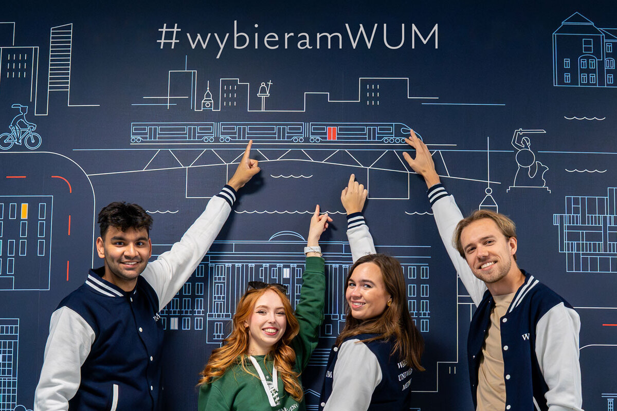 Copilot said: Four young people stand beside a colorful wall, pointing to the words “I Choose WUM.”