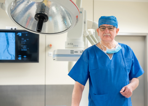 Mężczyzna w niebieskim kitlu na sali operacyjnej.