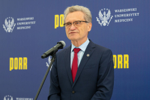 An older man in a suit at the microphone