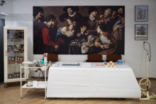 Sala muzealna. Na pierwszym planie leżanka lekarska oraz stolik z narzędziami medycznymi. Na ścianie reprodukcja obrazu "Lekcja anatomii". 