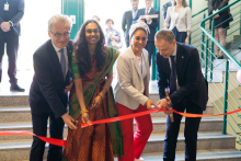 Two women and two men stand side by side on the stairs. Together they cut the red ribbon.