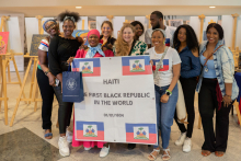 A group of ten mostly dark-skinned people are holding a poster with the inscription: Haiti the first black republic in the world.