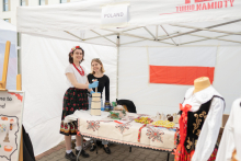 Polish stand. Two girls. One of them dressed in folk costume is churning butter.