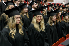 Uroczystość wręczenia dyplomów ukończenia studiów. Młode dziewczyny w togach i biretach akademickich.