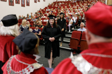 Graduates in black togas walk up to receive their diplomas.