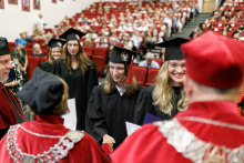 Graduates in black togas walk up to receive their diplomas.