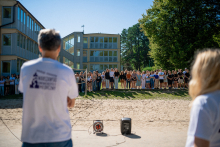 In the foreground two people with their backs turned. In the distance a group of young people.