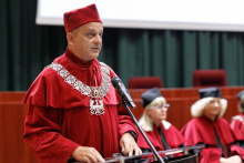 A man (pro-rector) in a red toga at the lectern.