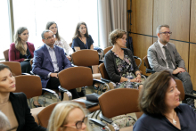 Middle-aged men and women sit on chairs.