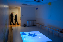 Pomieszczenie oddziału, na środku materac do rehabilitacji, światło w pomieszczeniu jest przygaszone i w kolorze niebieskim