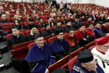 A collection of people of different ages dressed in academic attire of different colours.