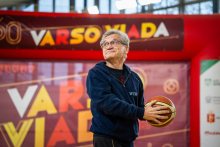 Mężczyzna w średnim wieku ubrany na sportowo trzyma w dłoniach piłkę do koszykówki, patrzy do góry przez ramię.