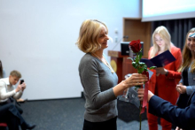 Kobieta odbiera czerwoną różę z rąk młodego mężczyzny