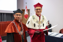 Na zdjęciu dwóch mężczyzn: dziekan i rektor, ubrani w togi akademickie.