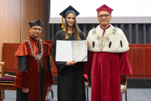 Na zdjęciu trzy osoby: w środku młoda kobieta, trzyma w rękach dyplom. Po jej obu stronach stoją mężczyźni - rektor i dziekan.