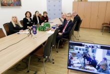 A group of people sitting at a table, with a video camera screen in the foreground.