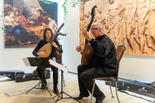 On stage, a woman and a man play lutes.