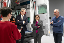 A group of four people stand in front of an ambulance simulator