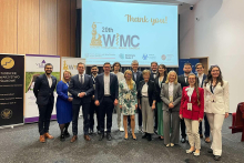 Grupa osób, w tym władz rektorskich i organizatorów. Stoją przed dużym ekranem, na którym wyświetlony jest tekst "Thank you!" oraz "20th WIMC Warsaw International Medical Congress". Są elegancko ubrani. Uśmiechają się do aparatu.