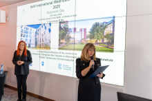 Dwie elegancko ubrane kobiety stojące przed dużym ekranem. Na ekranie wyświetlane są informacje o Dniu Endodontycznym organizowanym w ramach konferencji.