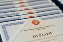 The photo shows the graduation diplomas of the Warsaw Medical University, neatly arranged in rows.