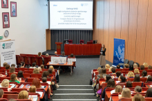 Lecture hall with participants seated in red chairs facing the podium and screen. On the screen, the WHO definition of stroke. On the left, the banner “National Conference on Clinical Logopaedics”.