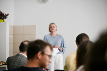 A woman speaking to a group of listeners.
