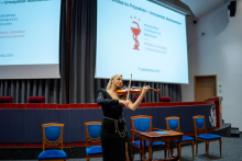 A woman is playing the violin on stage during the graduation ceremony.