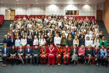 A group of young people—students, the dean, vice deans, vice rector, and others—are dressed formally and posing for a photo. The people in the front row—university and faculty authorities and invited guests—are seated, while the others are standing.