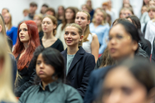 A large group of elegantly dressed young women and men. They are standing in the auditorium and taking their oaths.