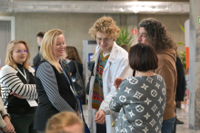 Sześć osób stojących w pomieszczeniu i rozmawiających w grupie.