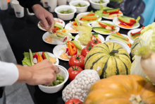 A table with a variety of fresh vegetables and small plates with sliced vegetables and dipping sauce. The table includes tomatoes, peppers, cucumbers, lettuce, pumpkins, and zucchinis.