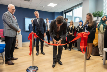 The dean cutting the ribbon. Behind him and beside him stand the other participants of the event.