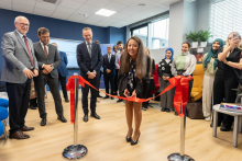 The head of the dean's office cutting the ribbon. Behind her and next to her stand the other participants of the event.