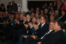 Uczestnicy gali. Elegancko ubrane osoby, siedzą w dużej sali i biją brawo.