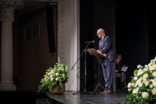 Rektor stoi na scenie i przemawia do mikrofonu.