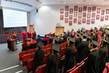 View of the auditorium. Graduates dressed in gowns are standing in rows. In the center of the hall stand the rector’s and dean’s authorities.