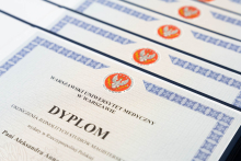 Several diplomas arranged in a row on a light background. The documents are white with a decorative blue border and a red emblem at the top. The diplomas display the text “Warsaw Medical University.”