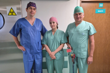 Three people wearing blue medical gowns pose for a photo. They are the people involved in the procedure.