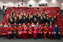 A group of graduates standing in rows throws academic caps. In the front rows sit the dean’s authorities, the vice-rector, and other invited guests.